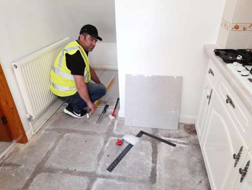 Handyman tiling a kitchen floor