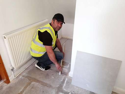 Handyman tiling near a radiator